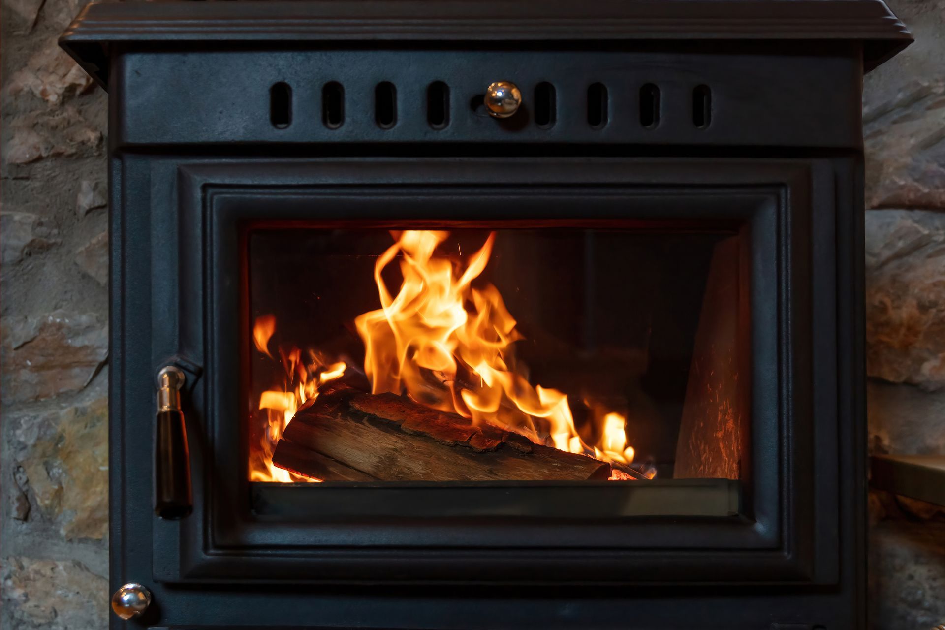 Poêle à bois noir avec un feu vif qui brûle à l'intérieur.