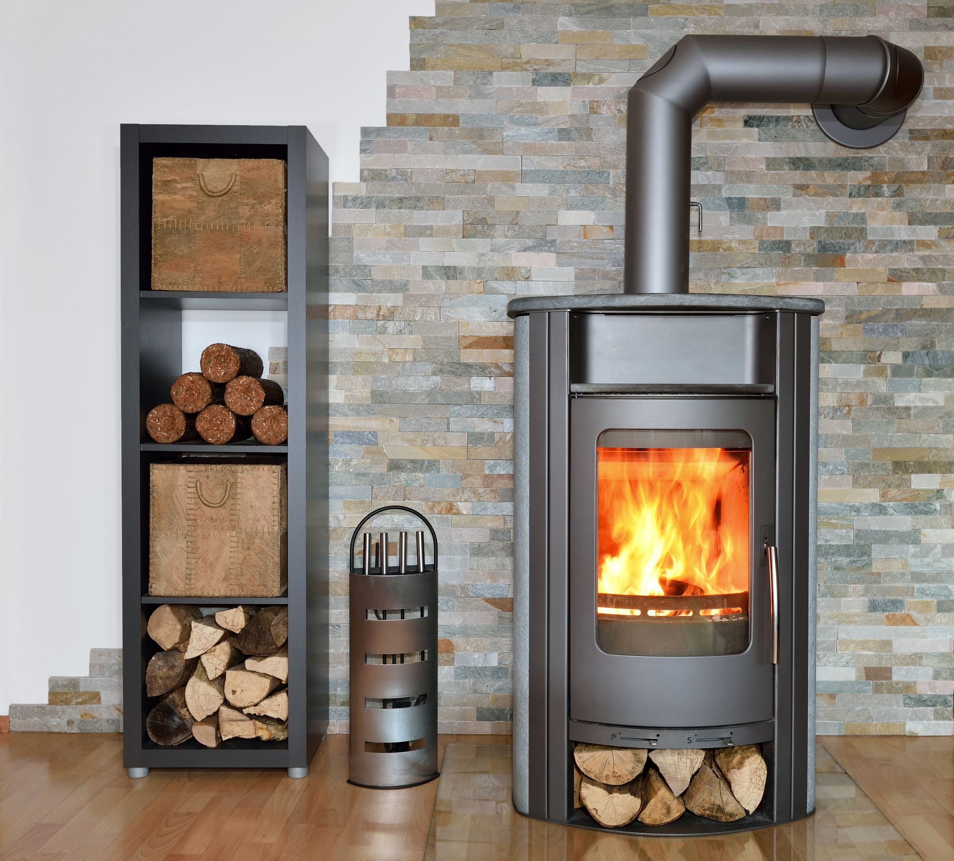 Poêle à bois moderne avec un feu qui brûle à côté d'un range-bûches noir et de bûches dans une pièce carrelée.