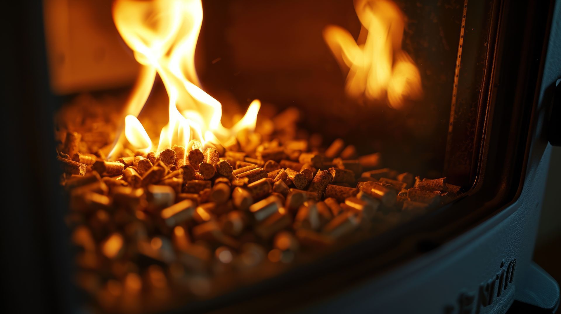 Gros plan sur des flammes orange brûlant à l'intérieur d'un poêle à bois en métal noir avec des braises incandescentes.
