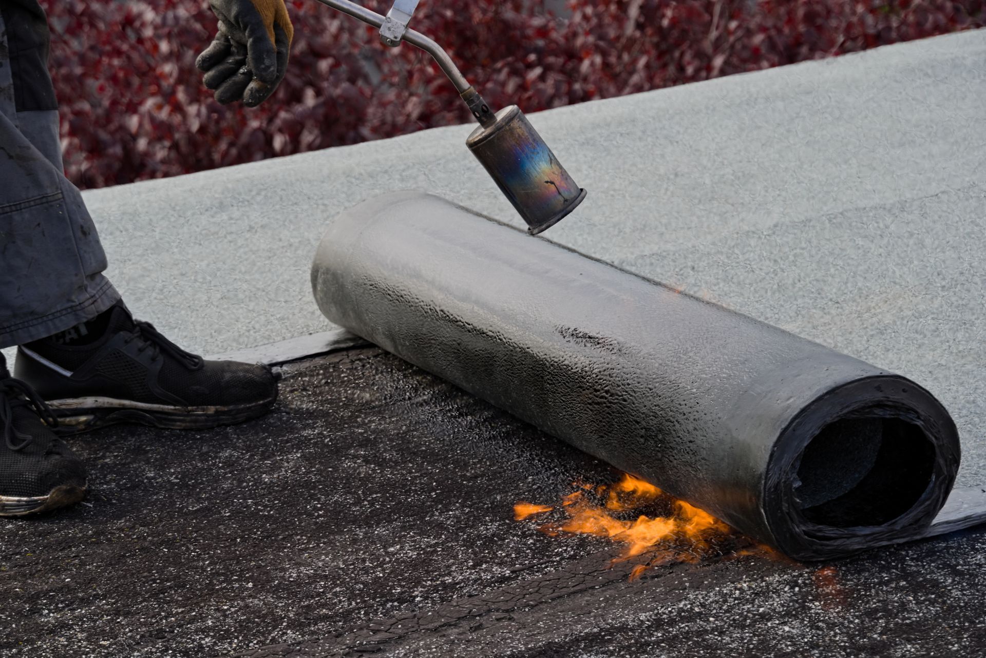 Rouleau de goudron et chalumeau, travaux en cours sur un toit plat