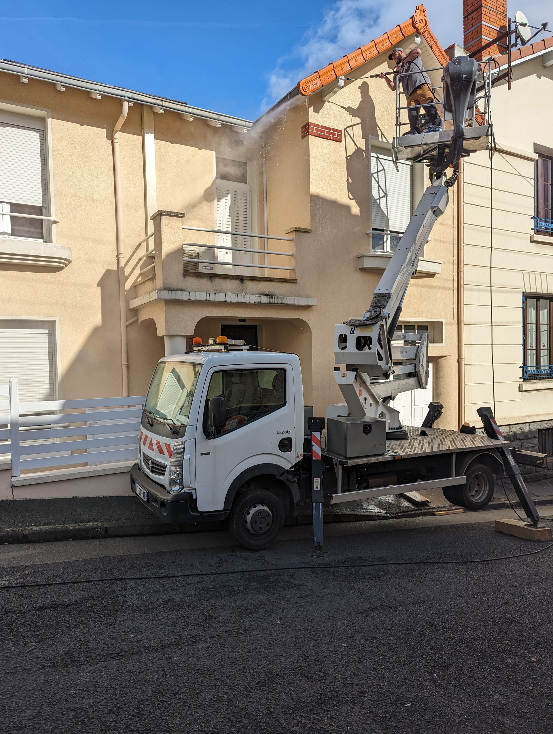 Suite du chantier de nettoyage : un couvreur nettoie l'avant toit et la couverture