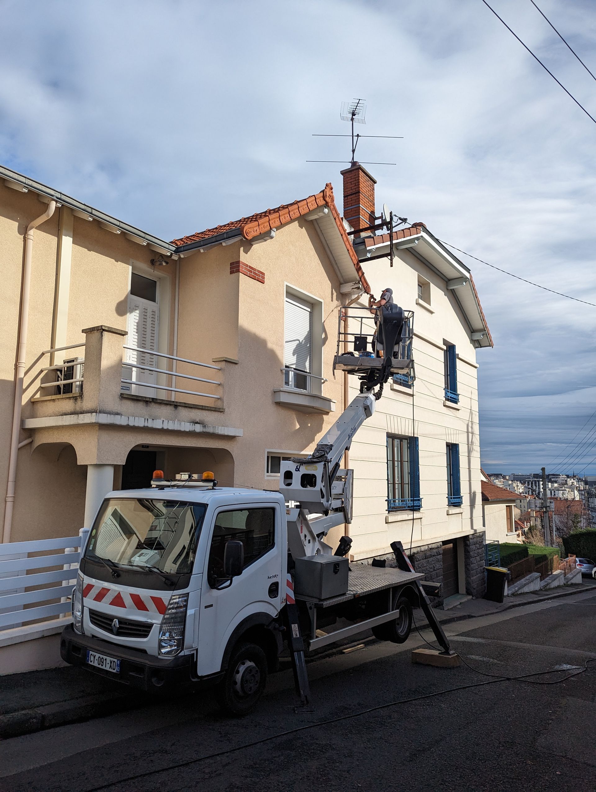 Chantier de nettoyage d'un toit à la vapeur, vue sur le camion nacelle, la façade et la couverture