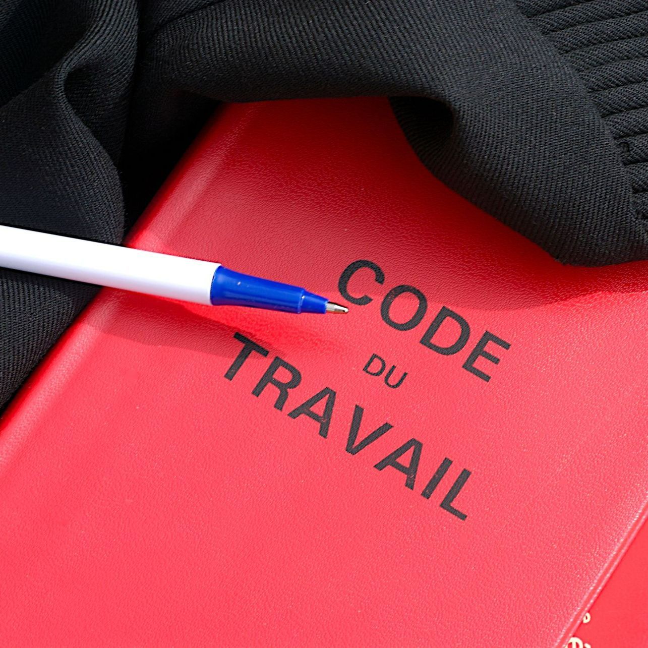 Livre rouge du Code du travail et un stylo posé dessus