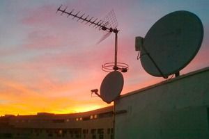 Dos antenas parabólicas están situadas en lo alto de un edificio al atardecer.