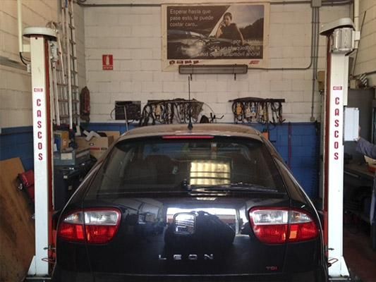 Un coche León está en un elevador en un garaje.