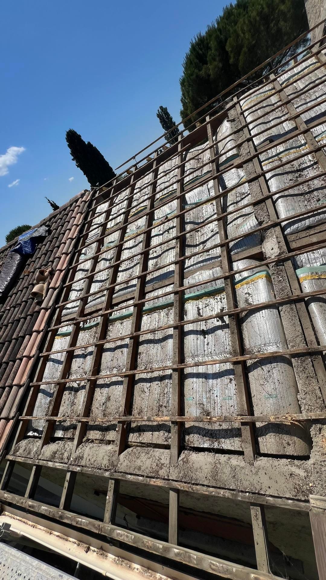 Portion de la charpente sans tuiles et au bois usé.