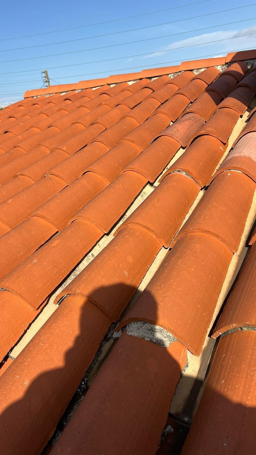 Gros plan sur des tuiles où l'on aperçoit l'ombre du photographe.