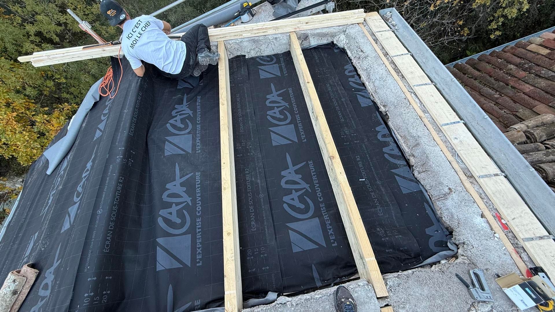 Personne de dos sur une charpente protégée par une bâche de couleur noire.