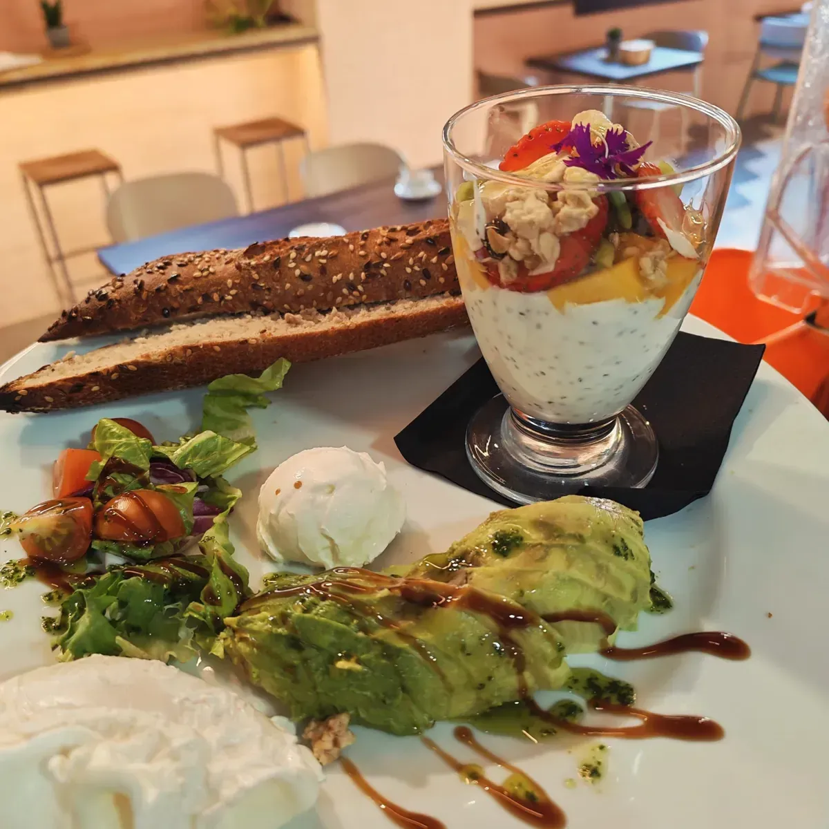 Plato de postre con pastel de chocolate, parfait de frutas y crepe verde en una mesa de restaurante.
