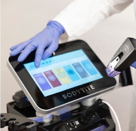 Una persona que lleva guantes azules está usando un dispositivo Bodytite.