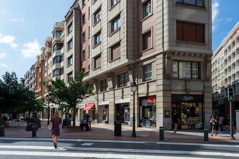 Una mujer está cruzando una calle frente a un edificio.
