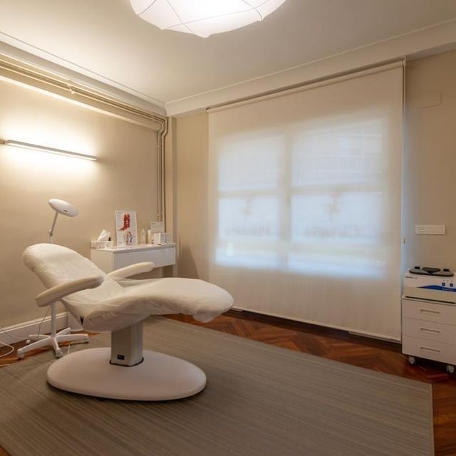 Una silla blanca está sentada en una habitación al lado de una ventana.