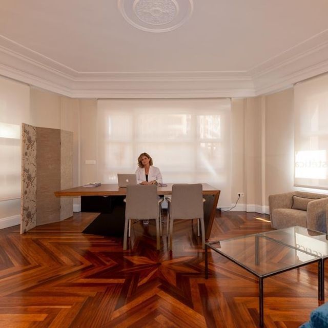 Una mujer se sienta en un escritorio con una computadora portátil en una sala de estar.