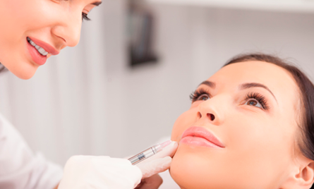 Una mujer recibe una inyección de botox en los labios.