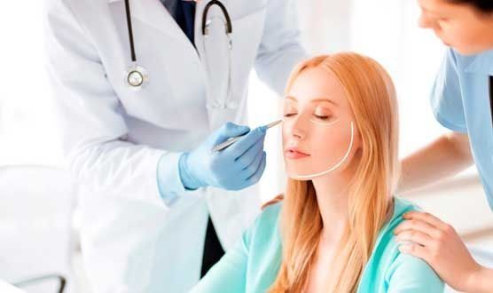 Una mujer está siendo operada de la cara por un médico.