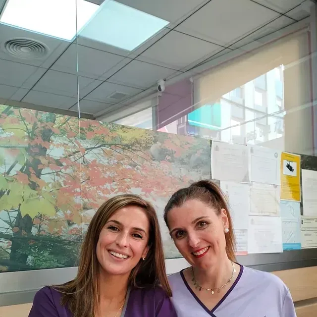 Dos mujeres posan para una foto delante de un cuadro.