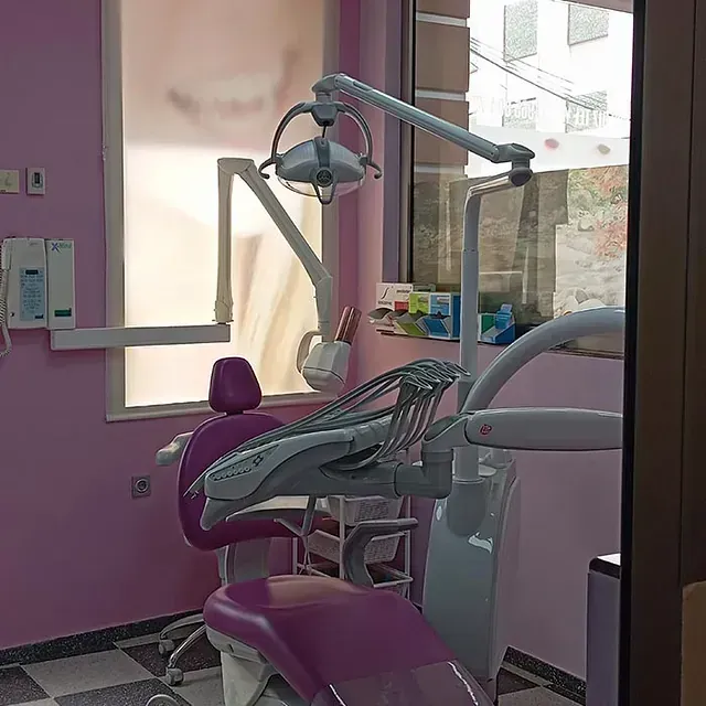 Un consultorio dental con una silla morada y una ventana.