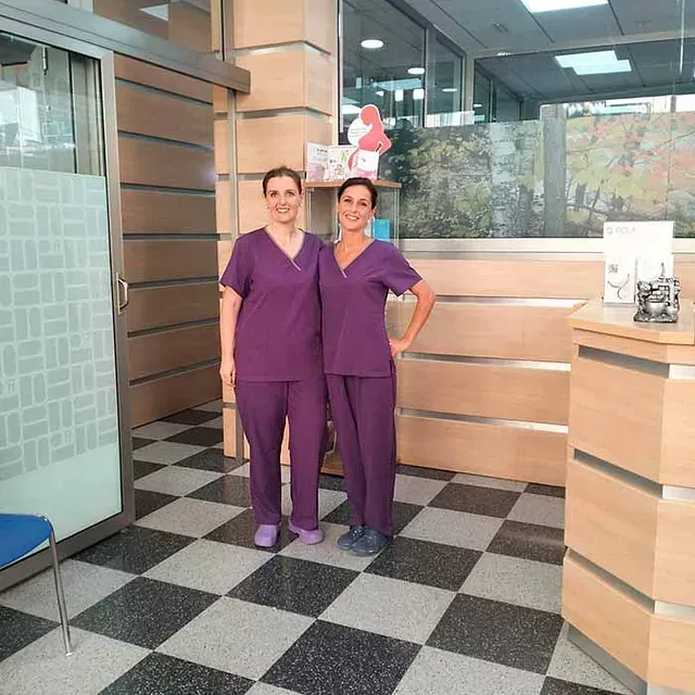 Dos mujeres con uniformes morados están paradas una al lado de la otra.