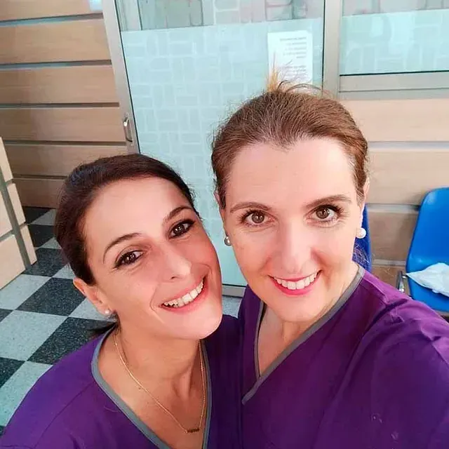 Dos mujeres con uniformes morados sonríen para una foto.