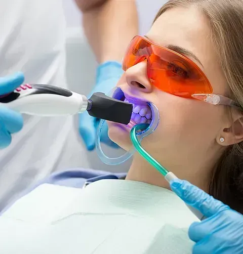 Una mujer se está blanqueando los dientes con un dentista.