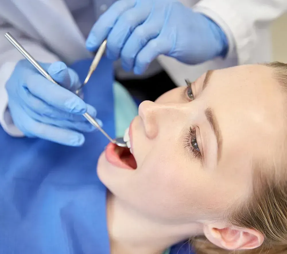 Una mujer está siendo examinada por un dentista.
