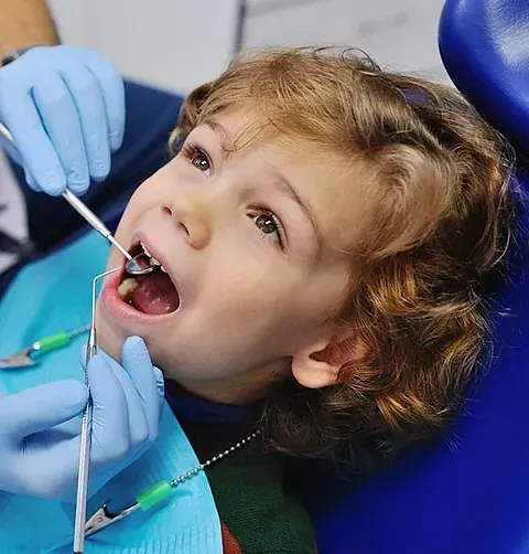 A un niño pequeño le están examinando los dientes un dentista.