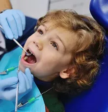 A un niño pequeño le están examinando los dientes un dentista.