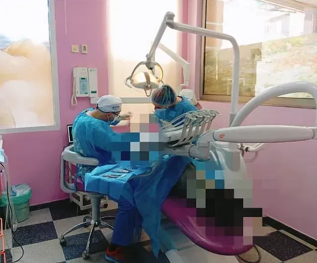 Dos dentistas están trabajando en un paciente en un consultorio dental.