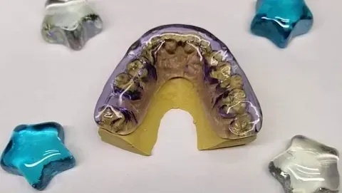 Un modelo dental de los dientes de una persona está rodeado de estrellas azules y plateadas.
