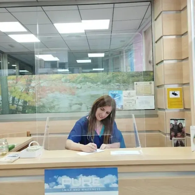 Una mujer se sienta en un escritorio con un cartel que dice puro