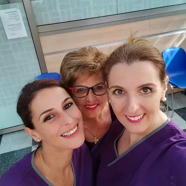 Tres mujeres vestidas con uniformes morados posan para una foto.