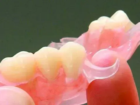 Un primer plano de una dentadura postiza sobre un fondo verde.