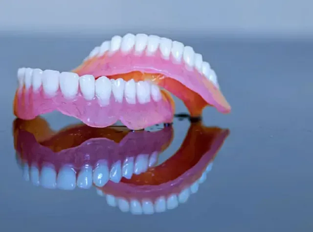 Un par de dentaduras postizas están colocadas una encima de otra sobre una mesa.