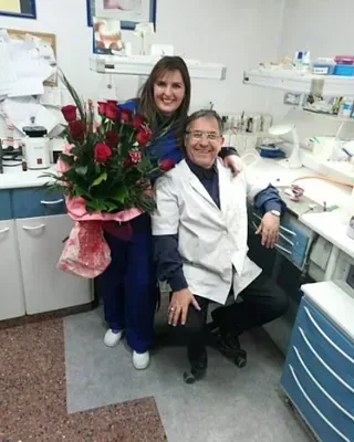 Una mujer sostiene un ramo de rosas junto a un hombre.