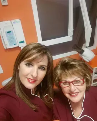 Dos mujeres posan para una fotografía en un consultorio dental.