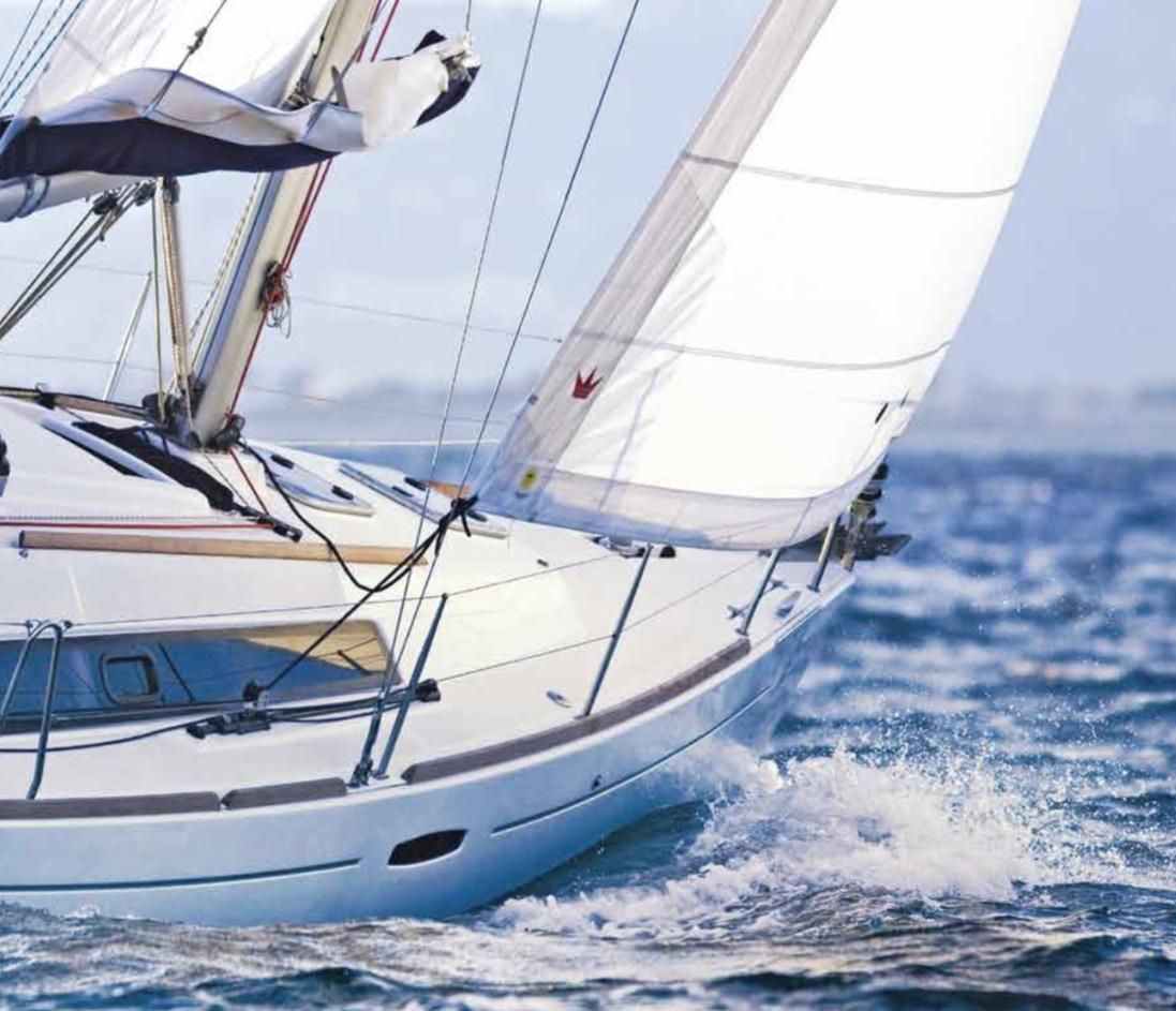 Un velero blanco surcando las olas azules del océano bajo un cielo brillante.