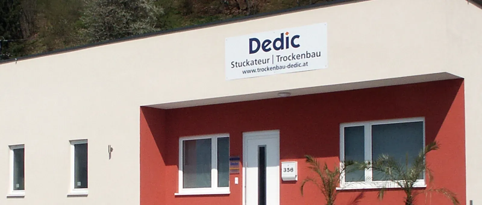 Außenansicht eines rot-weißen Gebäudes mit einem „Dedic“-Schild über dem Eingang