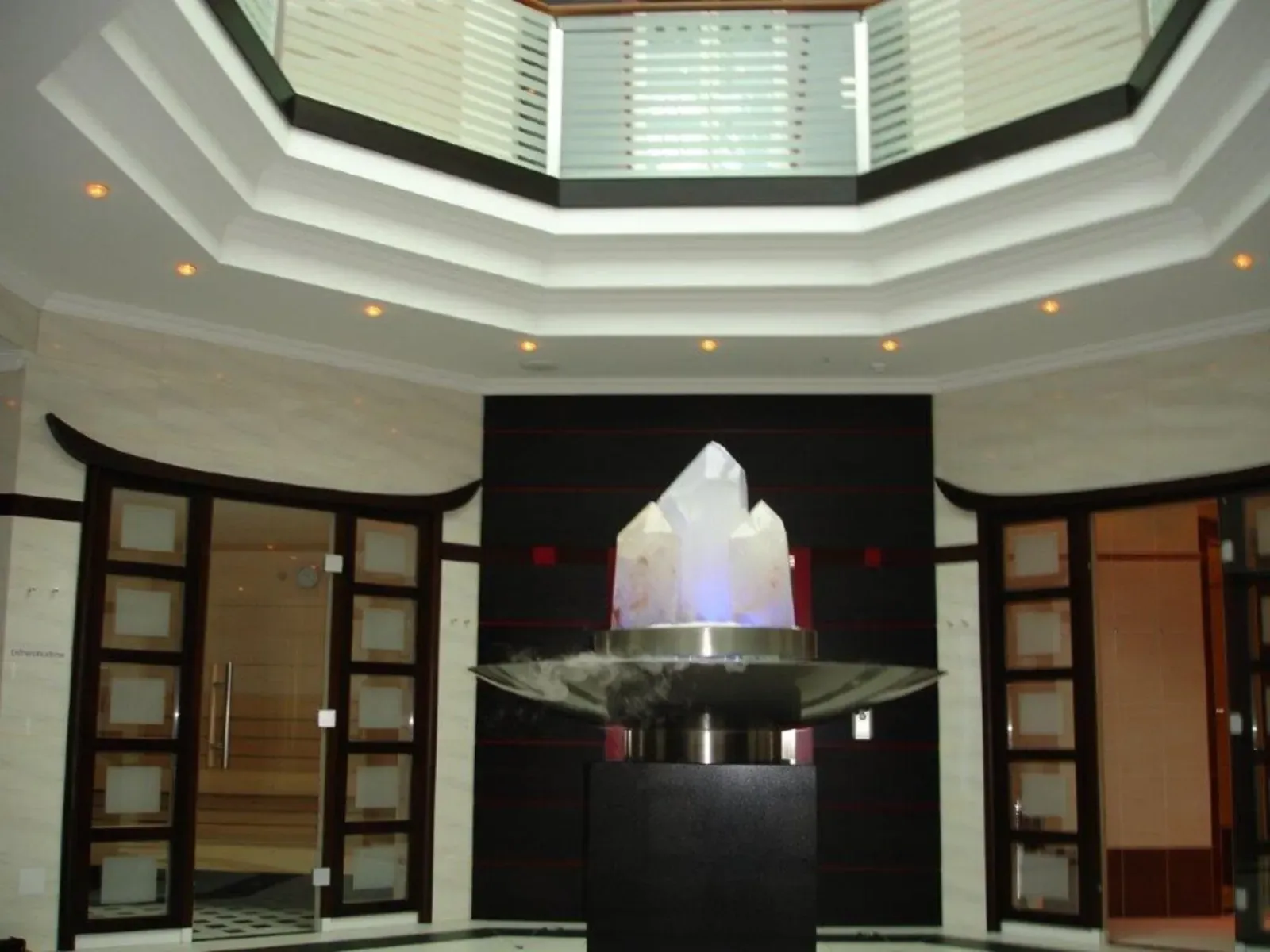 Modernes Atrium mit achteckigem Oberlicht und zentraler, beleuchteter Brunnenskulptur