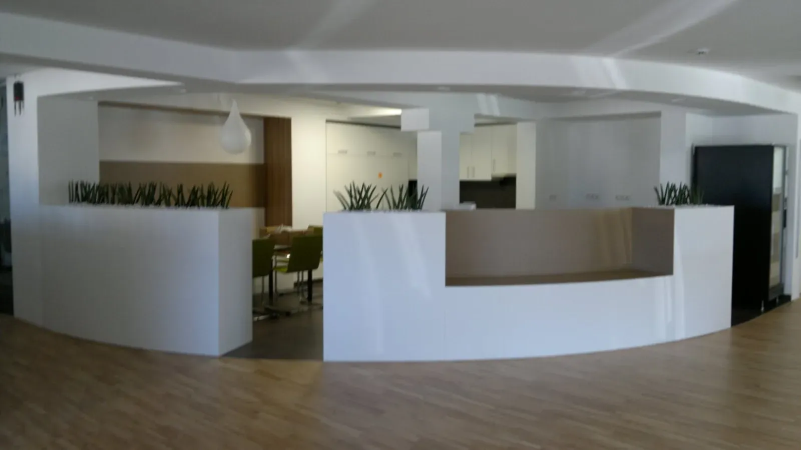 Moderne, minimalistische Lobby mit weißen, geschwungenen Empfangstresen, Holzboden und Lounge-Sitzgelegenheiten.