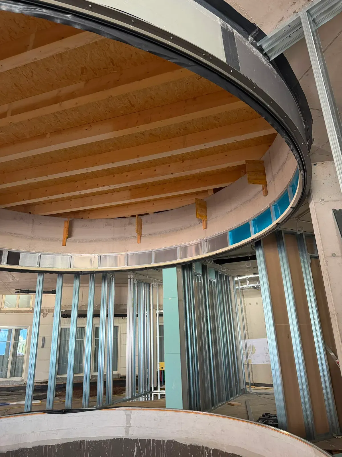 Modernes Interieur mit gewölbter Decke, sichtbaren Holzbalken, Glastrennwänden und blauen Akzenten