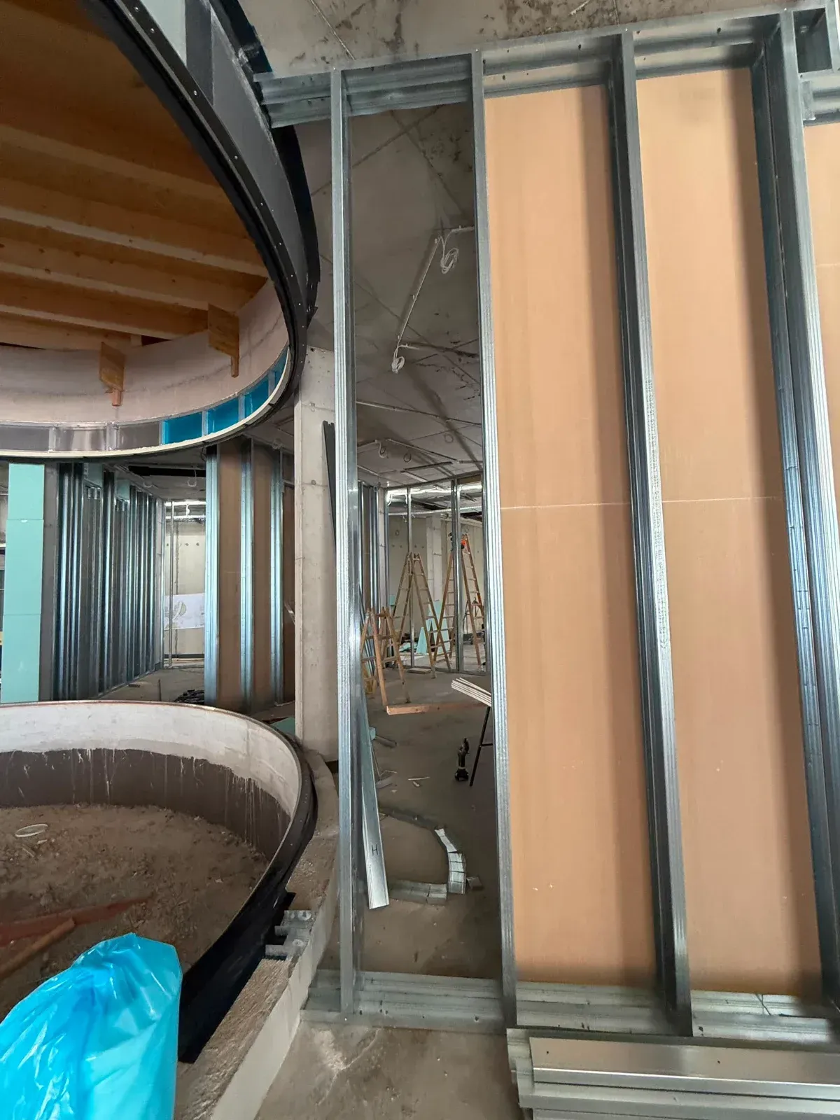 Innenausbau im Rohbau mit geschwungener Treppe, freiliegendem Metallgerüst und unfertigen Wänden