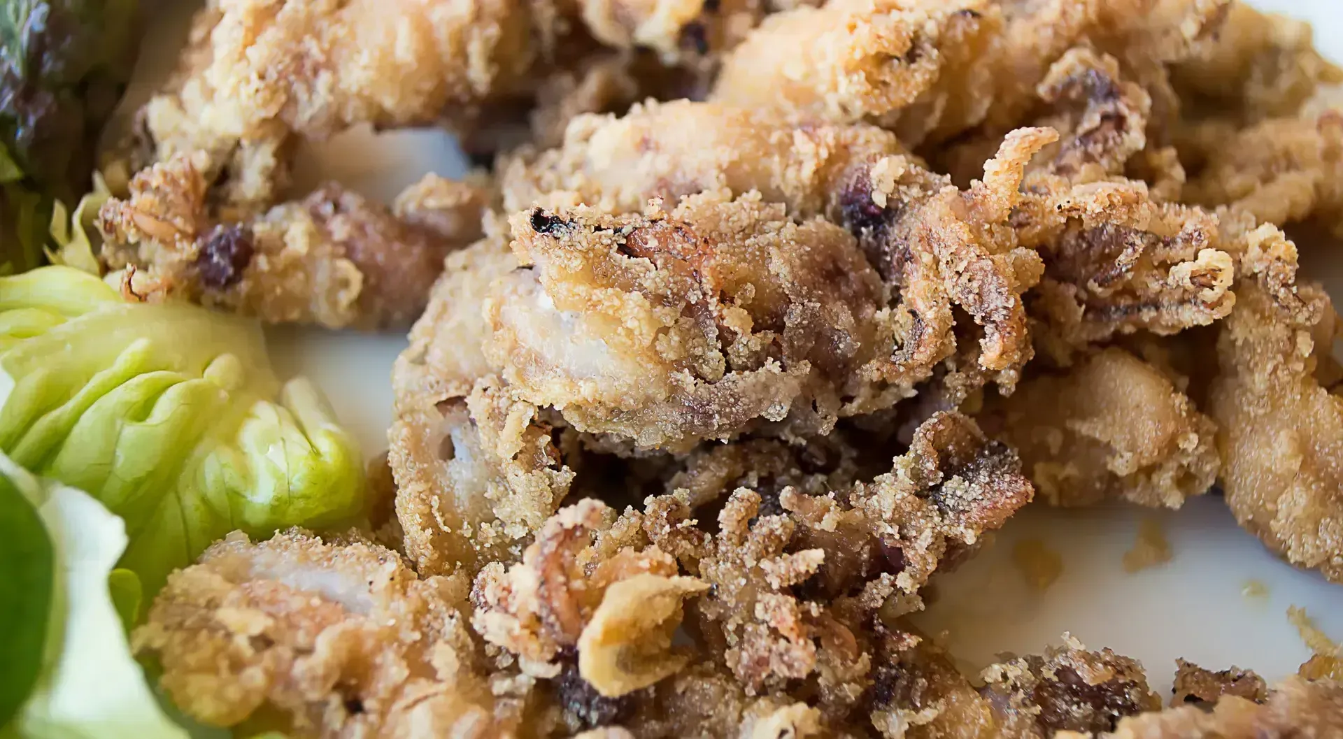 Calamares fritos con una capa dorada y crujiente, servidos con lechuga.