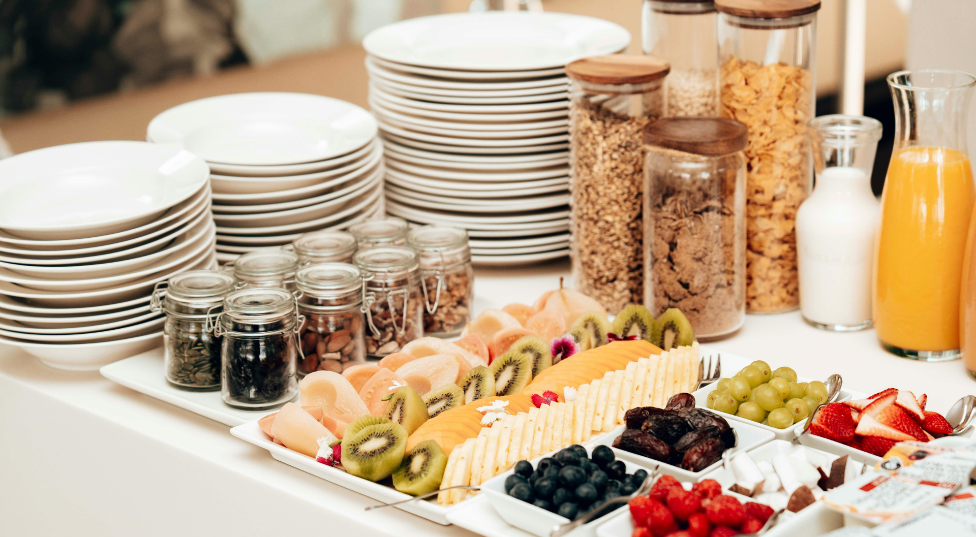 Desayuno buffet con platos preparados, cereales, fruta y zumo.
