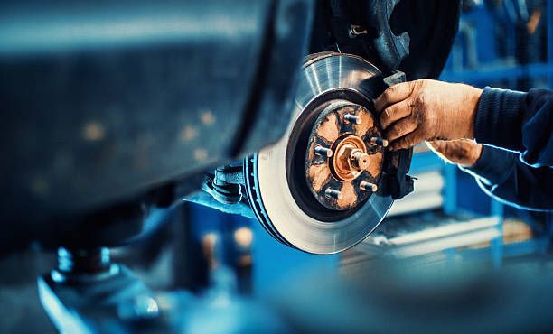 Un mecánico está arreglando un disco de freno de un coche en un garaje.