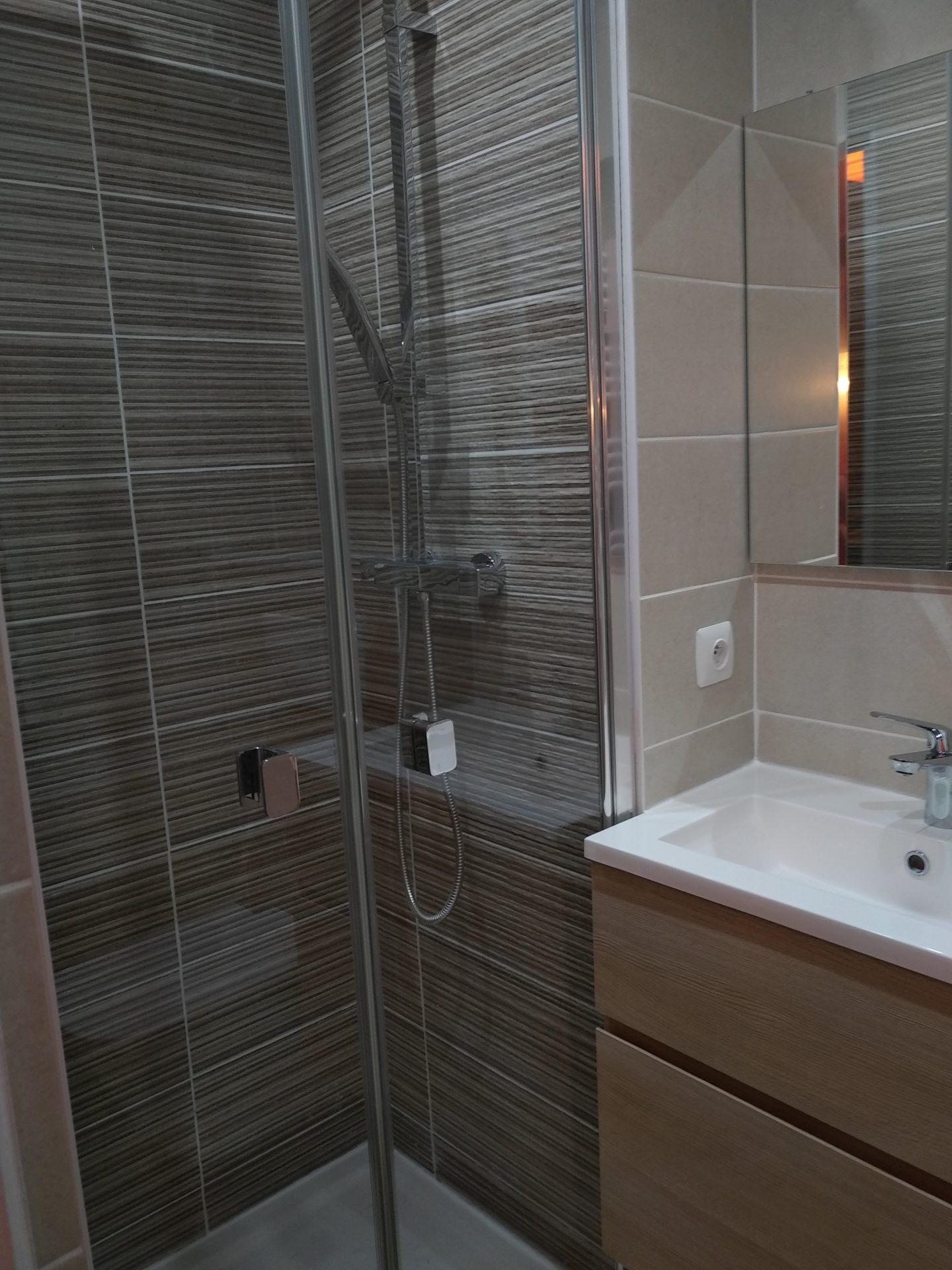 Une douche avec des grands carreaux de carrelage