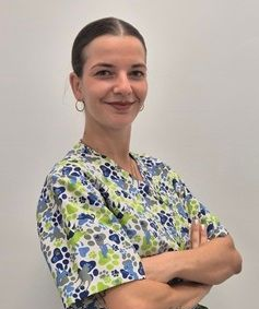 Una mujer con un uniforme azul posa para una fotografía con los brazos cruzados.