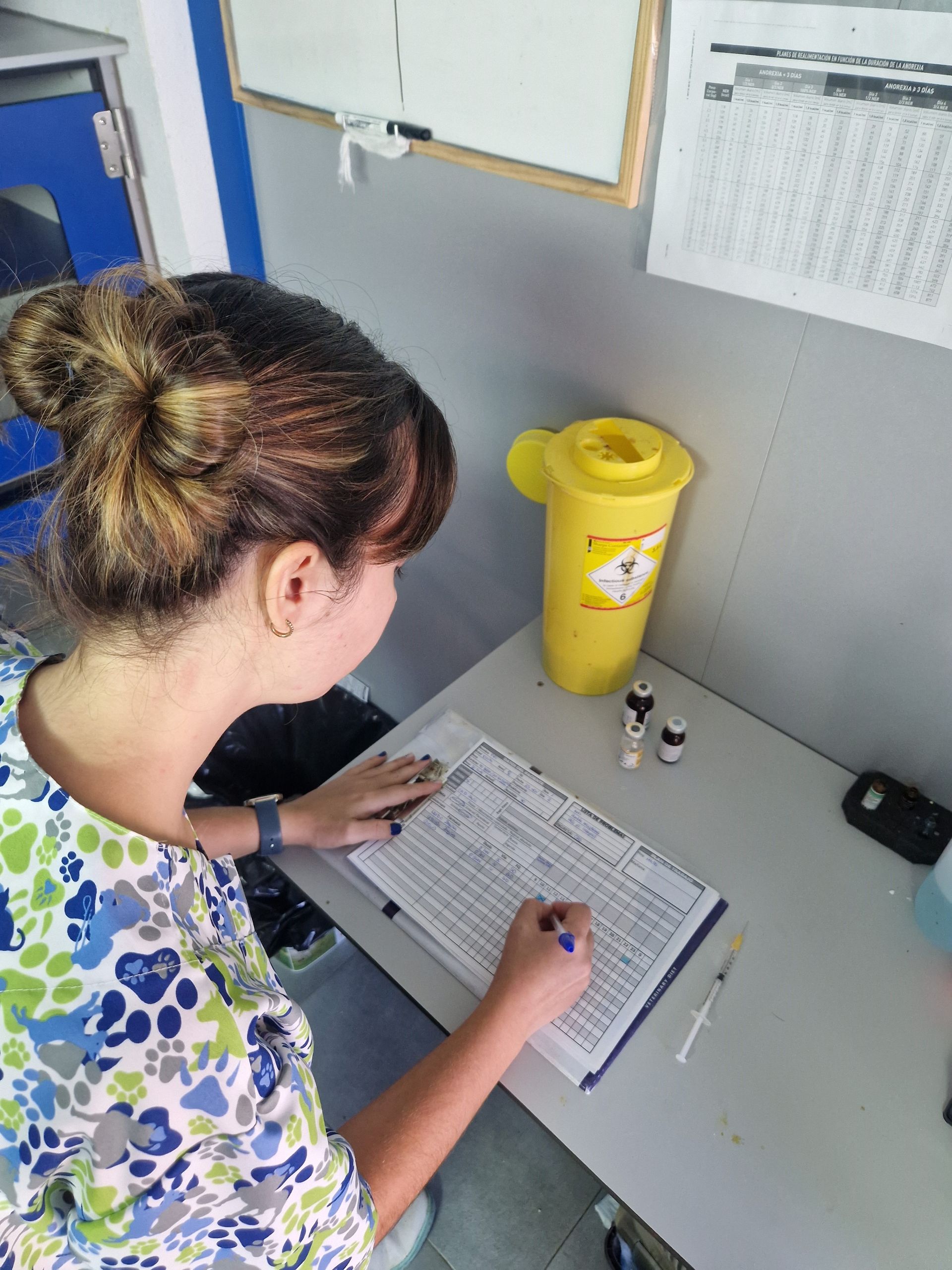 Una mujer está sentada en un escritorio escribiendo en un trozo de papel.
