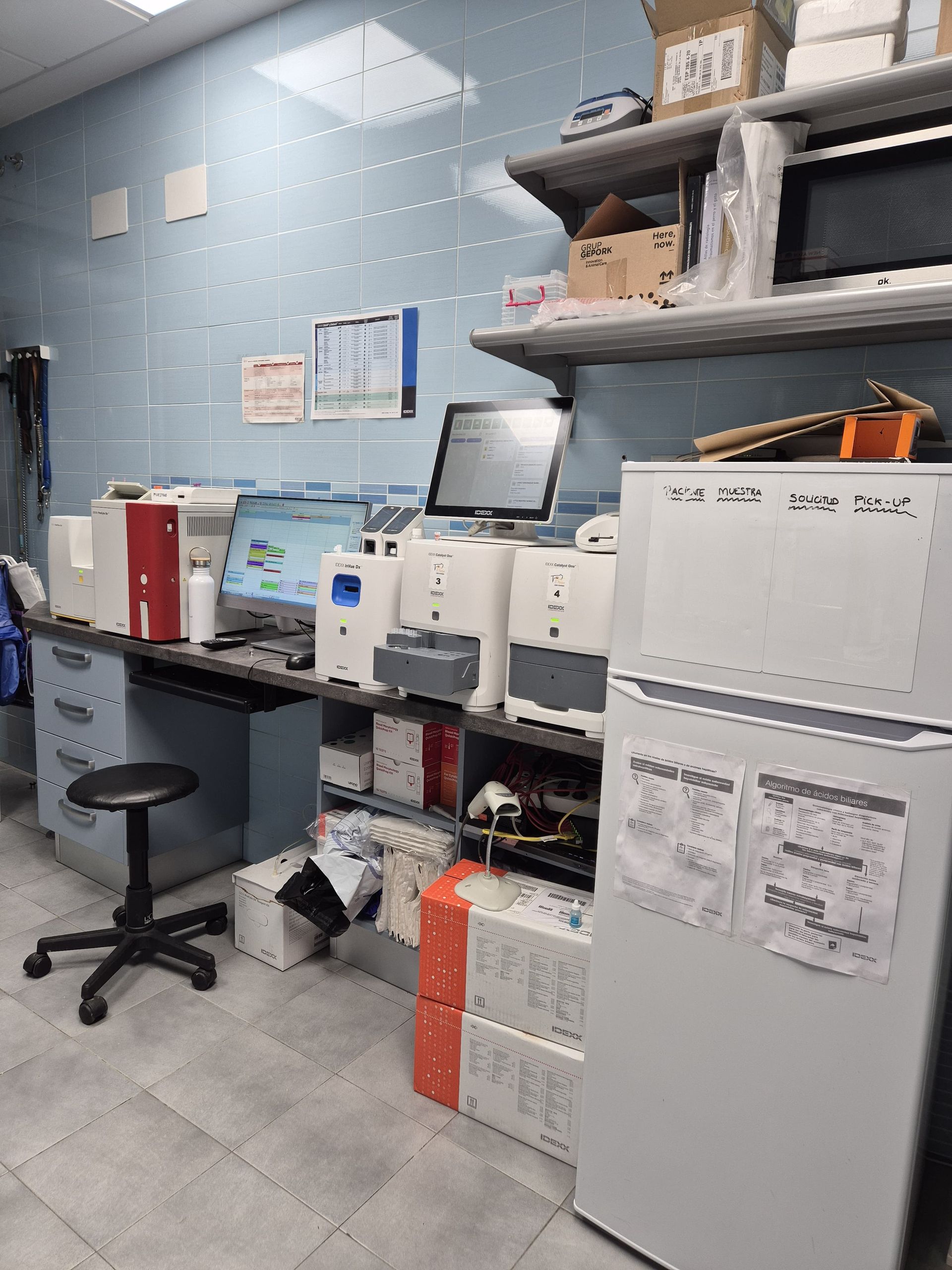 Una laboratorio con varias máquinas para la realización de analíticas sanguíneas y otros fluidos, y un ordenador en la encimera.