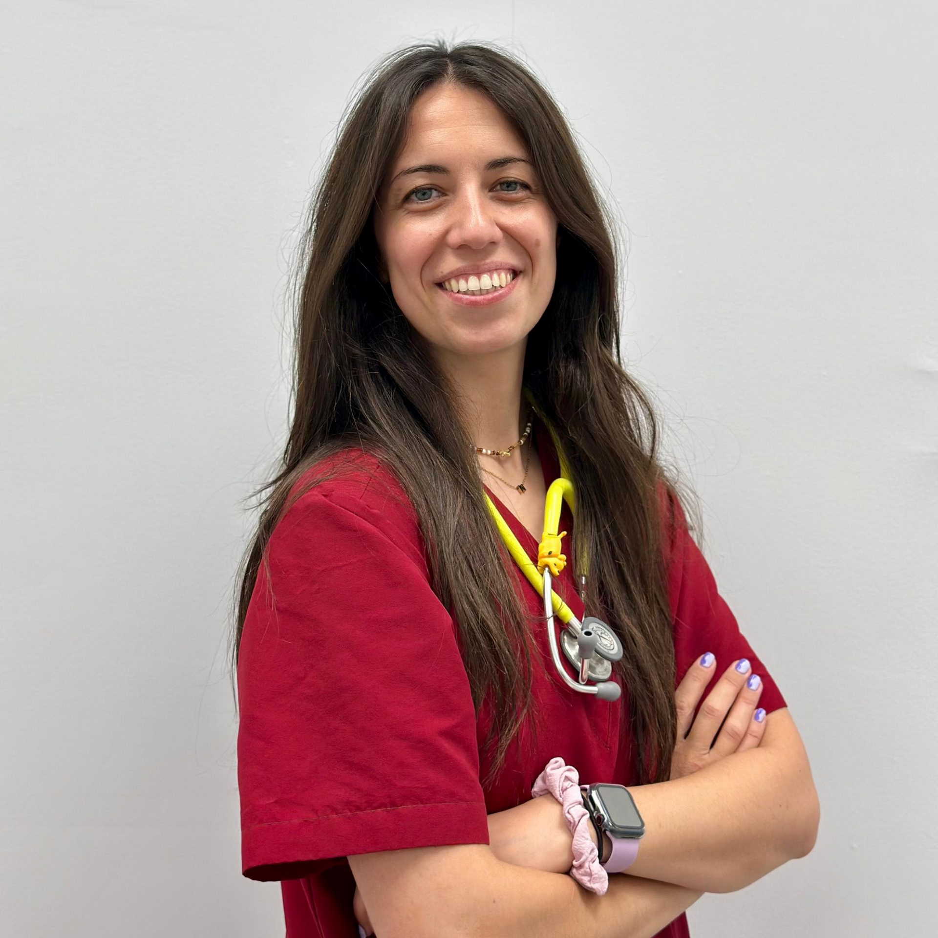 Una mujer con una camisa roja posa para una foto con los brazos cruzados.