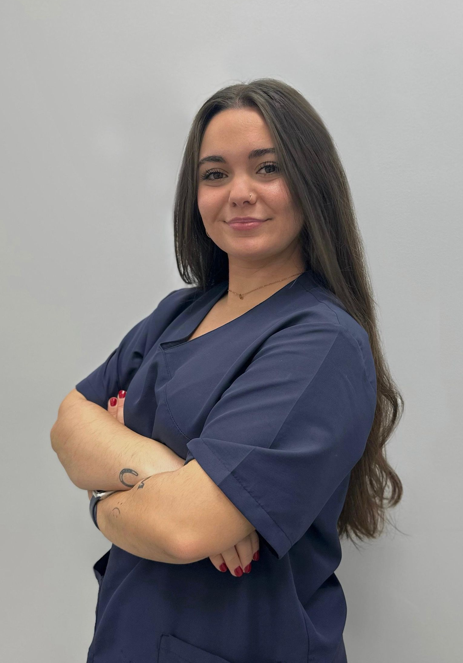 Una mujer con un uniforme azul posa para una fotografía con los brazos cruzados.